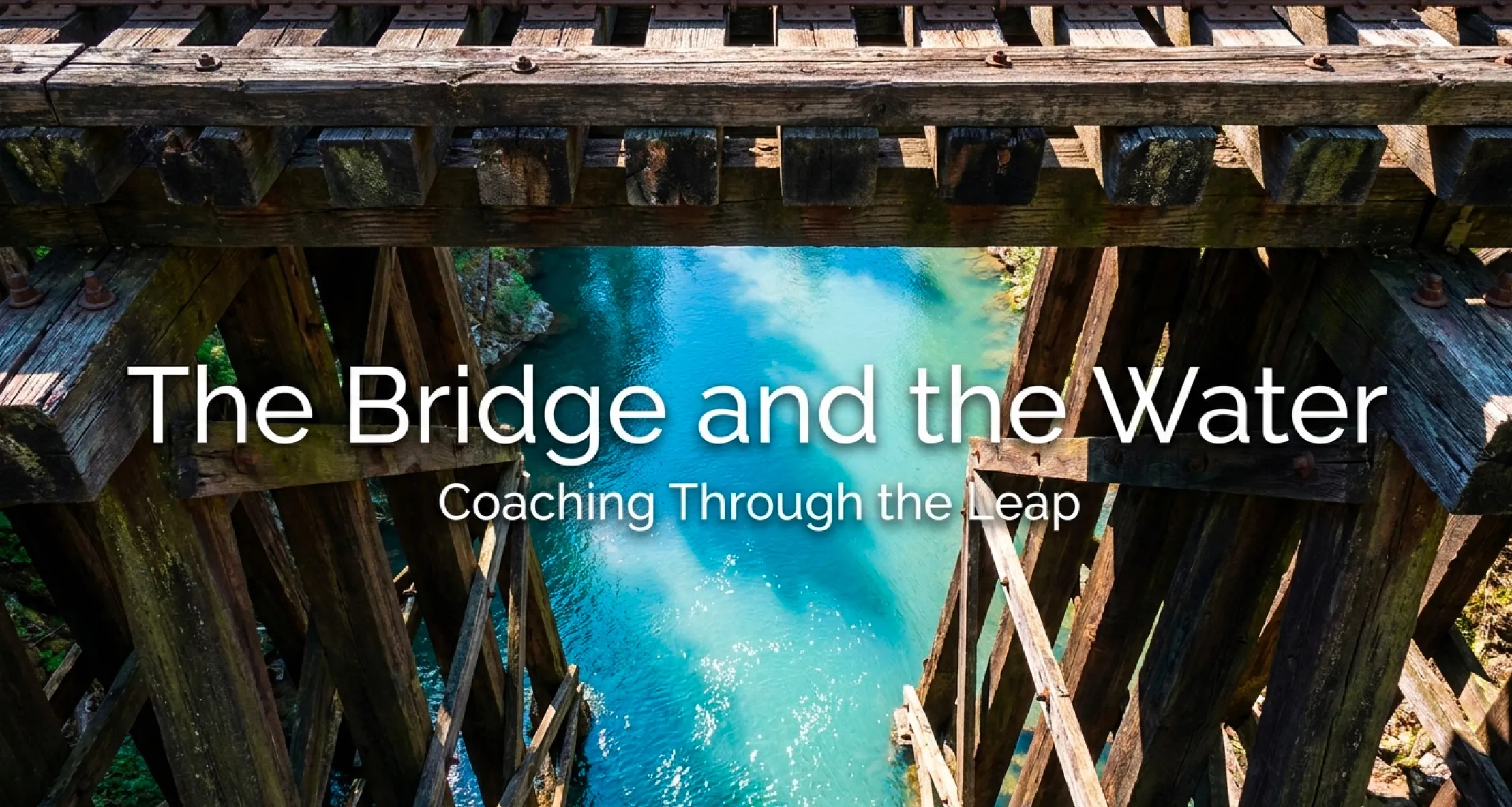 Looking down through the wooden ties of an old railroad trestle into bright teal water below, with the title 'The Bridge and the Water, Coaching Through the Leap' overlaid.